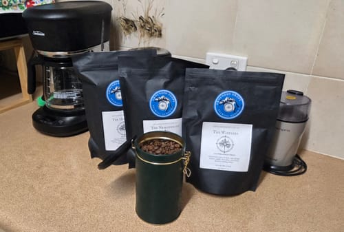 Grounded Drops coffee pouches beside a filter coffee machine on a kitchen bench