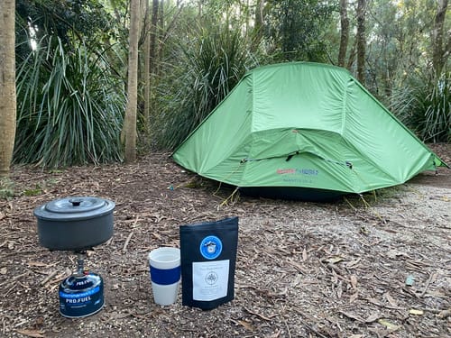 Camp stove and pot with a Grounded Drops pouch in front of a tent