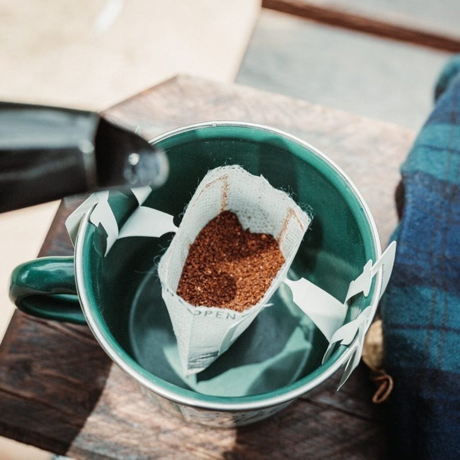 Grounded Drops drip coffee bag brewing in a green enamel mug